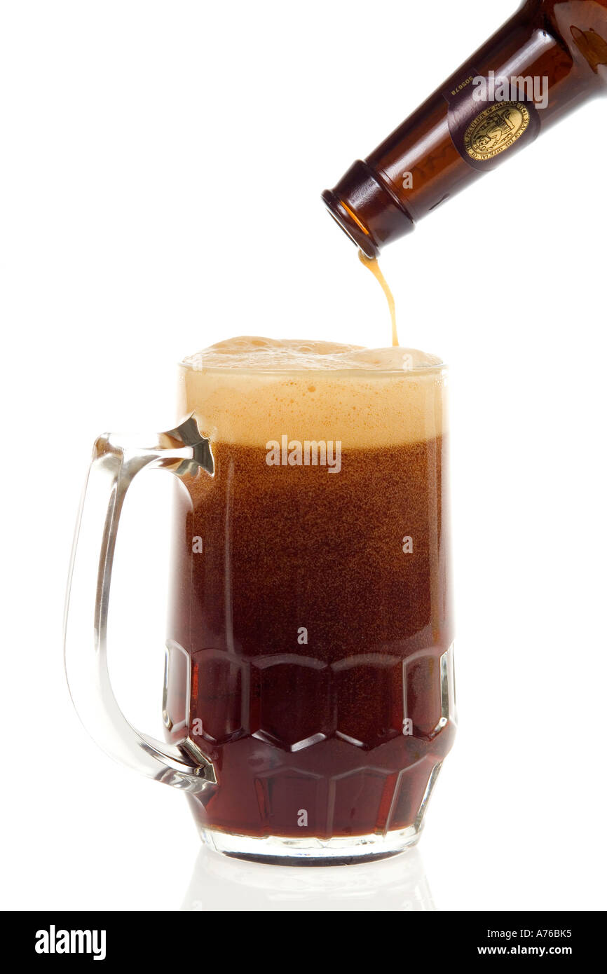 Pint of dark beer being poured into glass on a pure white background. Stock Photo