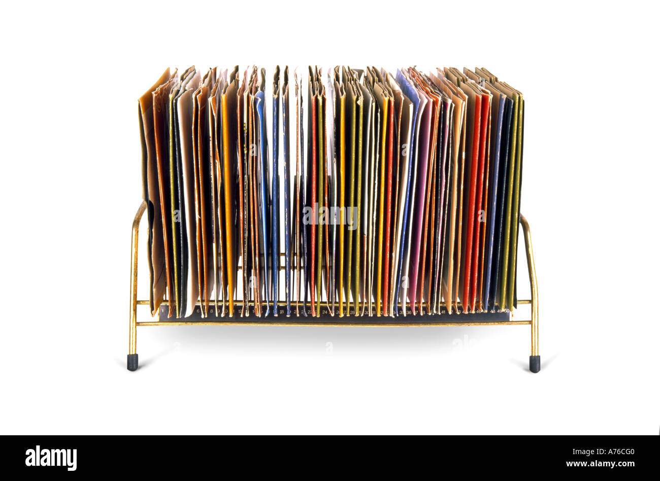 Side on view of old vinyl 45's records stacked in a kitsch seventies holder on a pure white background. Stock Photo
