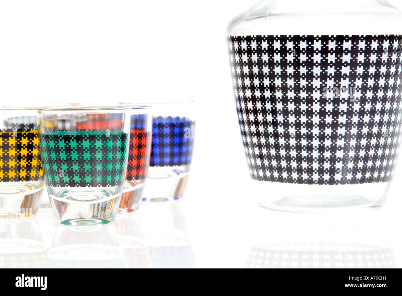 Retro coloured shot glasses and decanter on a pure white background