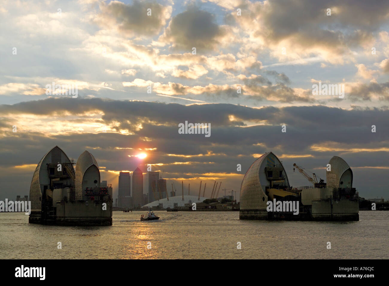 Sunset over the Thames Flood Barrier with the Millenium Dome now known as the o2 arena and Canary Wharf in the background. Stock Photo