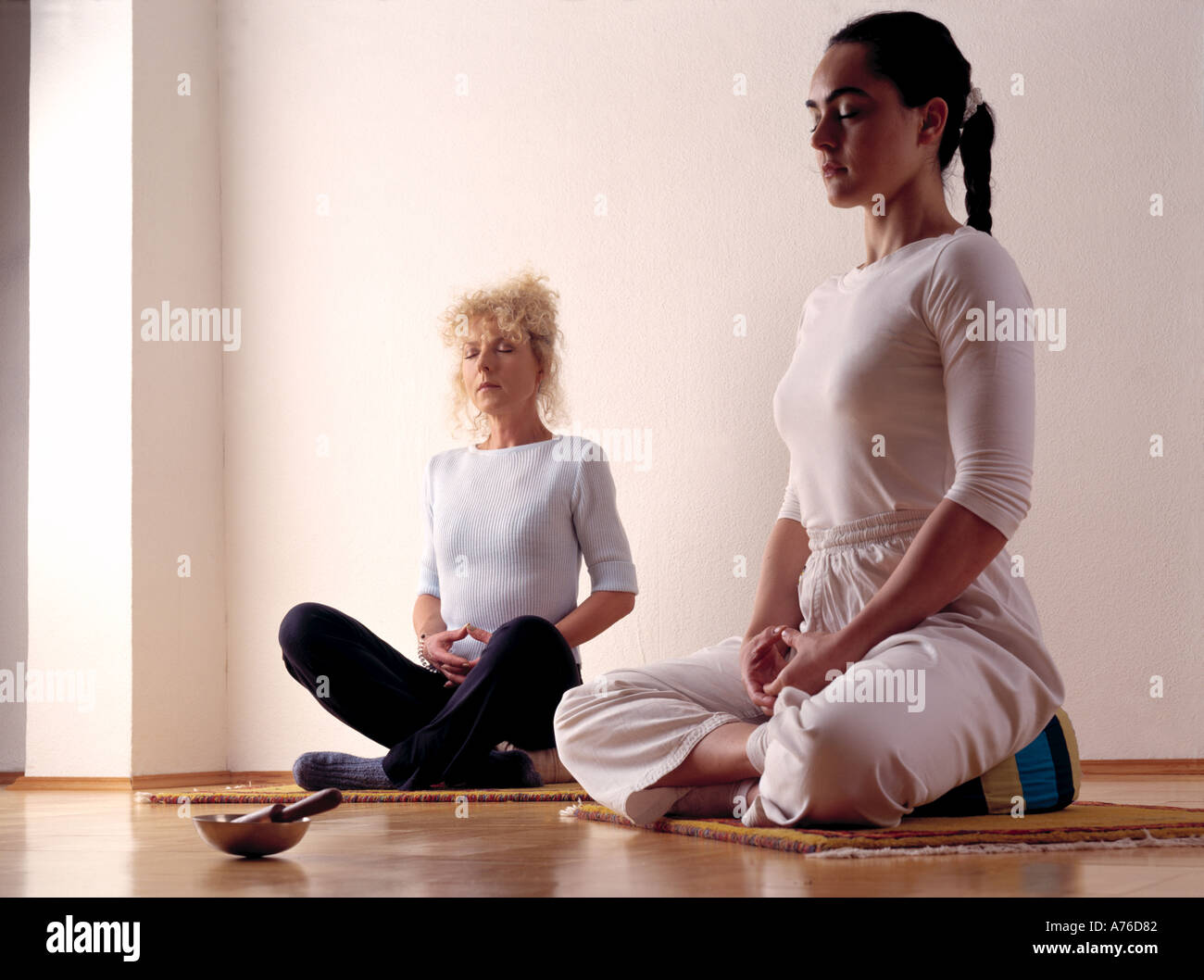 Two women meditating in a white room Stock Photo
