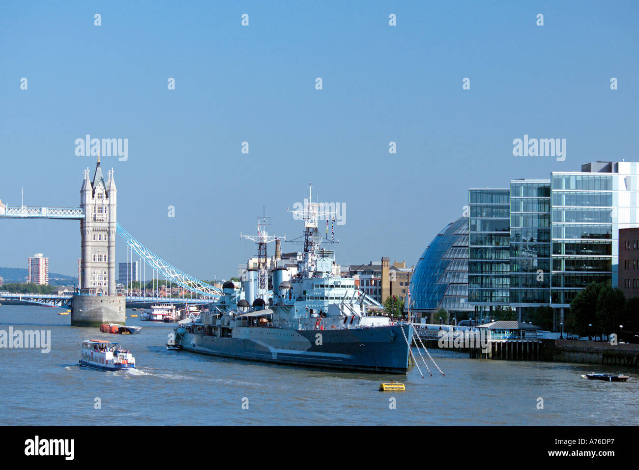 A view of the Thames with City Hall, Tower Bridge, HMS Belfast and a pleasure boat against a blue sky. Stock Photo