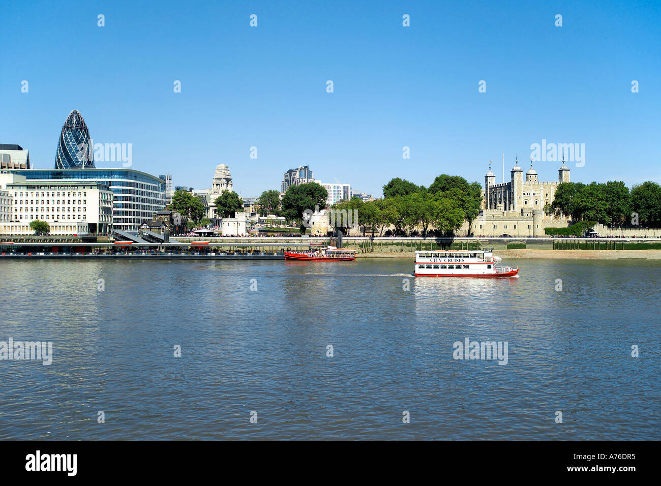 Wide view of the Thames north bank including the Swiss Re building and the Tower of London with a tourist boat on the river. Stock Photo