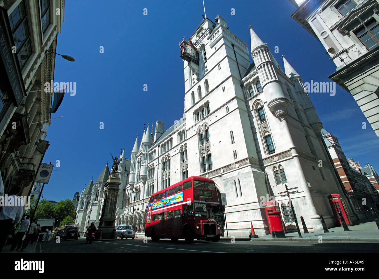 Low wide angle of a traditional red double decker route master bus passing the Royal Courts of Justice aka Law Courts in London. Stock Photo