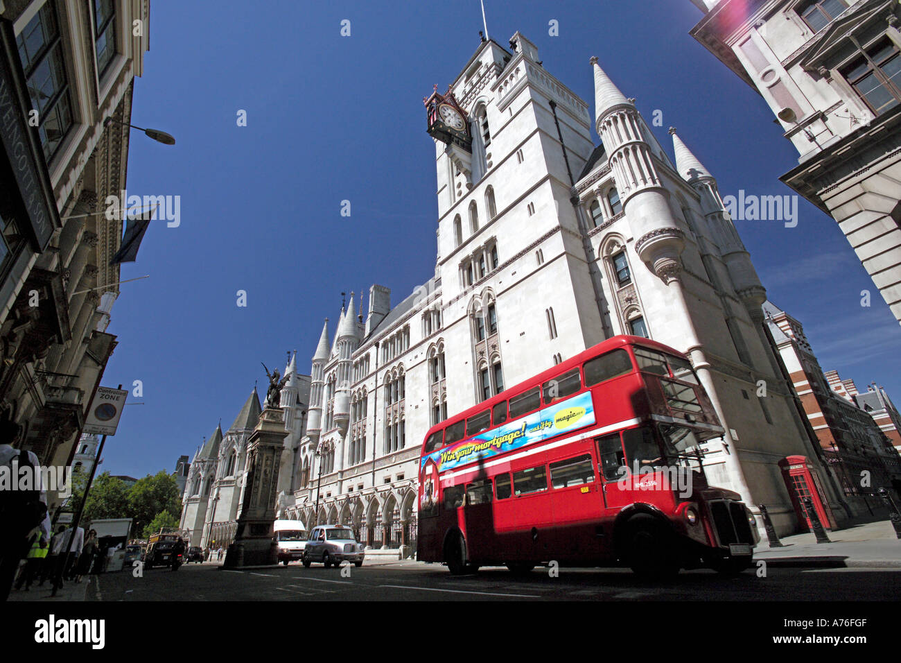 Low wide angle of a traditional red double decker route master bus passing the Royal Courts of Justice aka Law Courts in London. Stock Photo