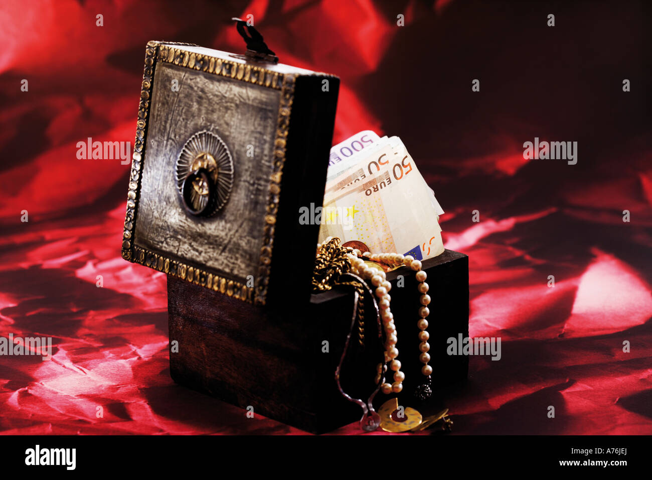 Treasure box full of money and jewellery Stock Photo