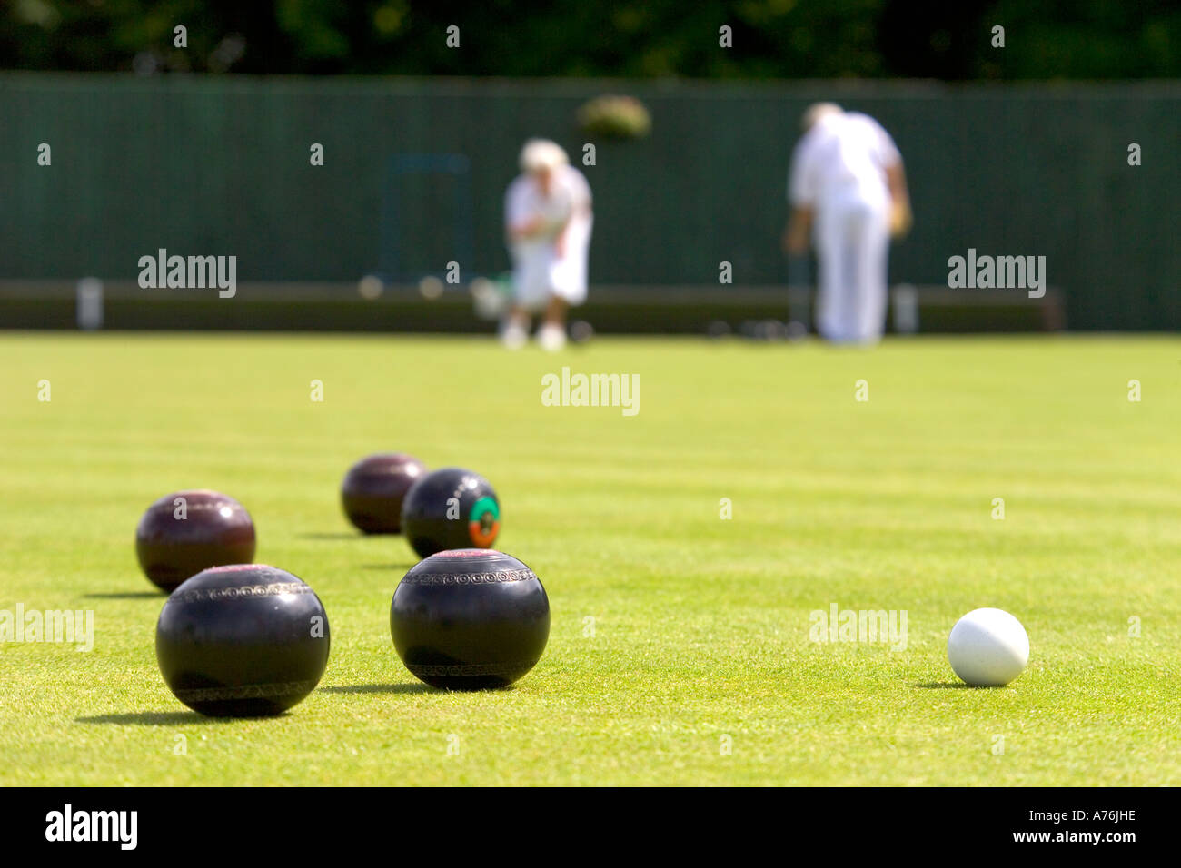 Close up of bowls and jack during a game with blurred team members in the background. Stock Photo