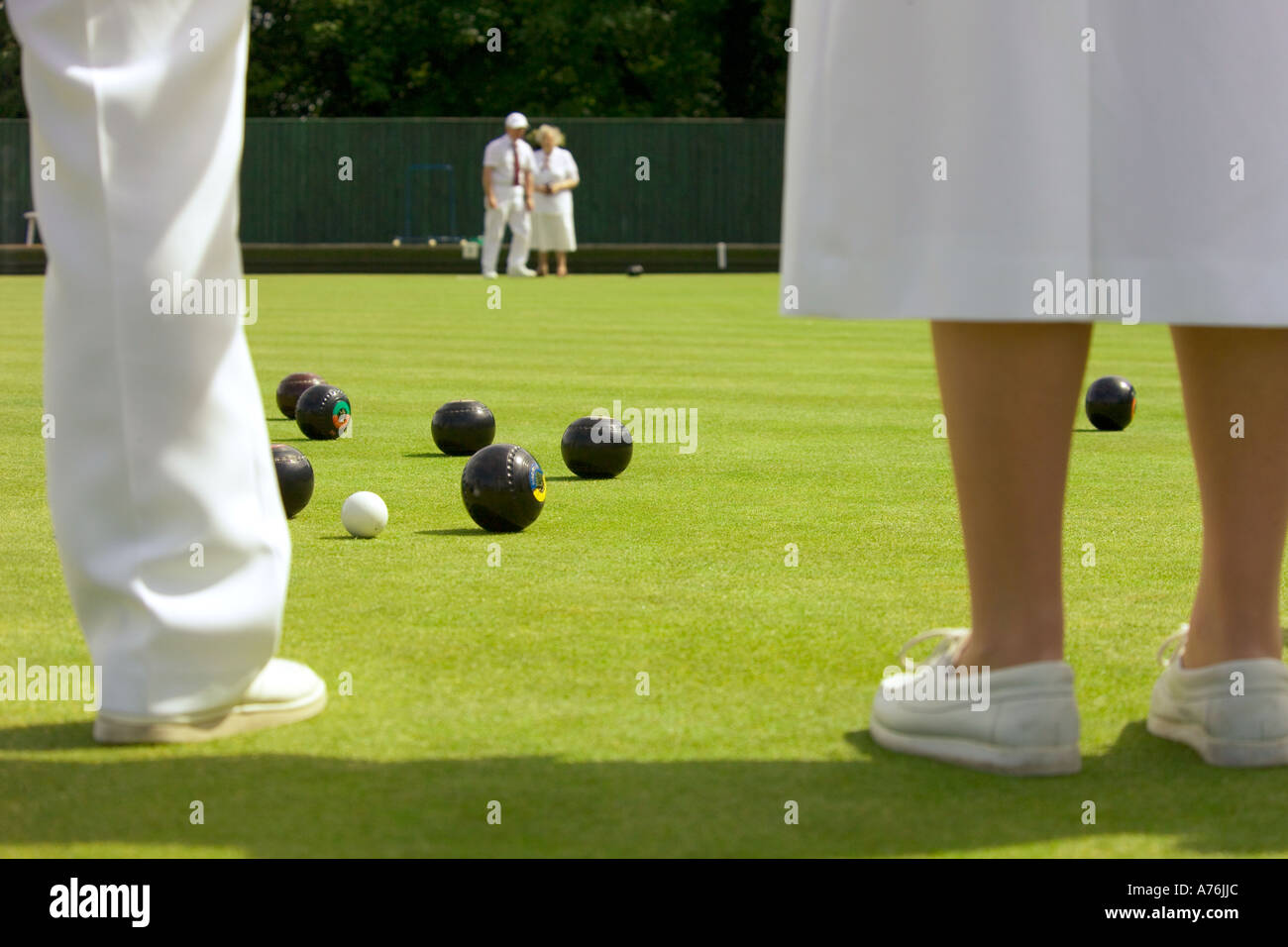 Close up of team members legs, bowls and jack during a game. Stock Photo