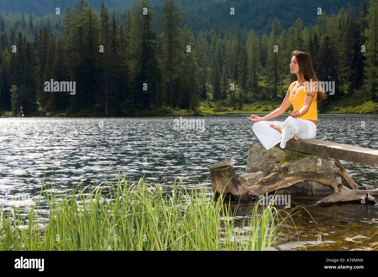 Woman exercising yoga at lake, side view Stock Photo