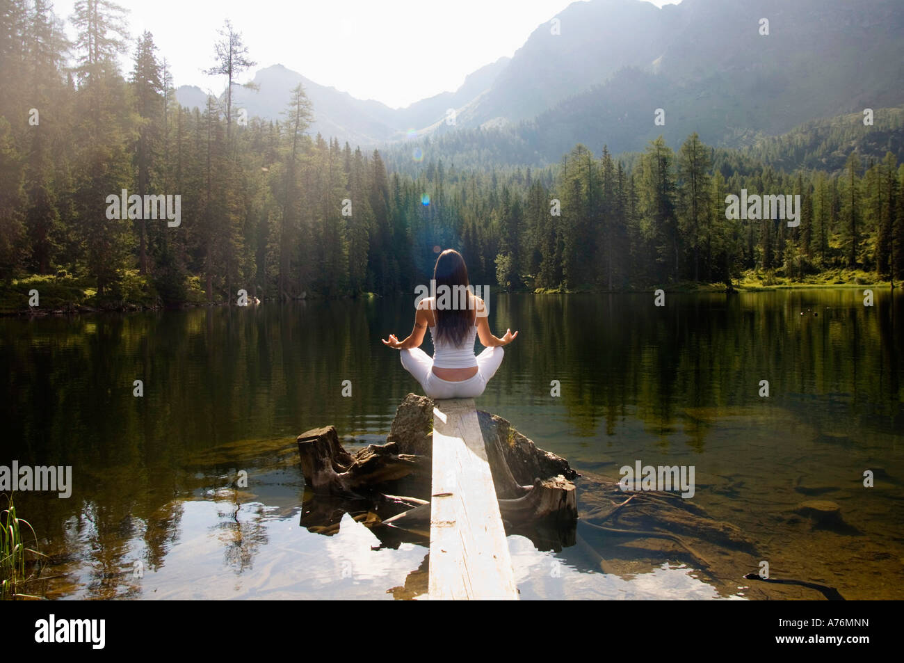 Woman exercising yoga at lake, rear view Stock Photo