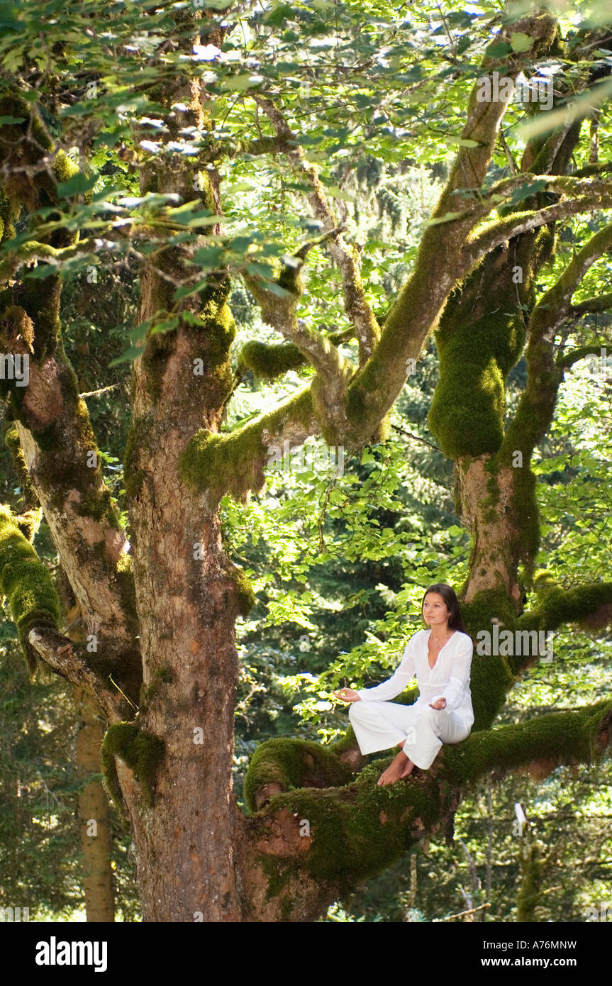 Young woman meditating on tree branch, side view Stock Photo