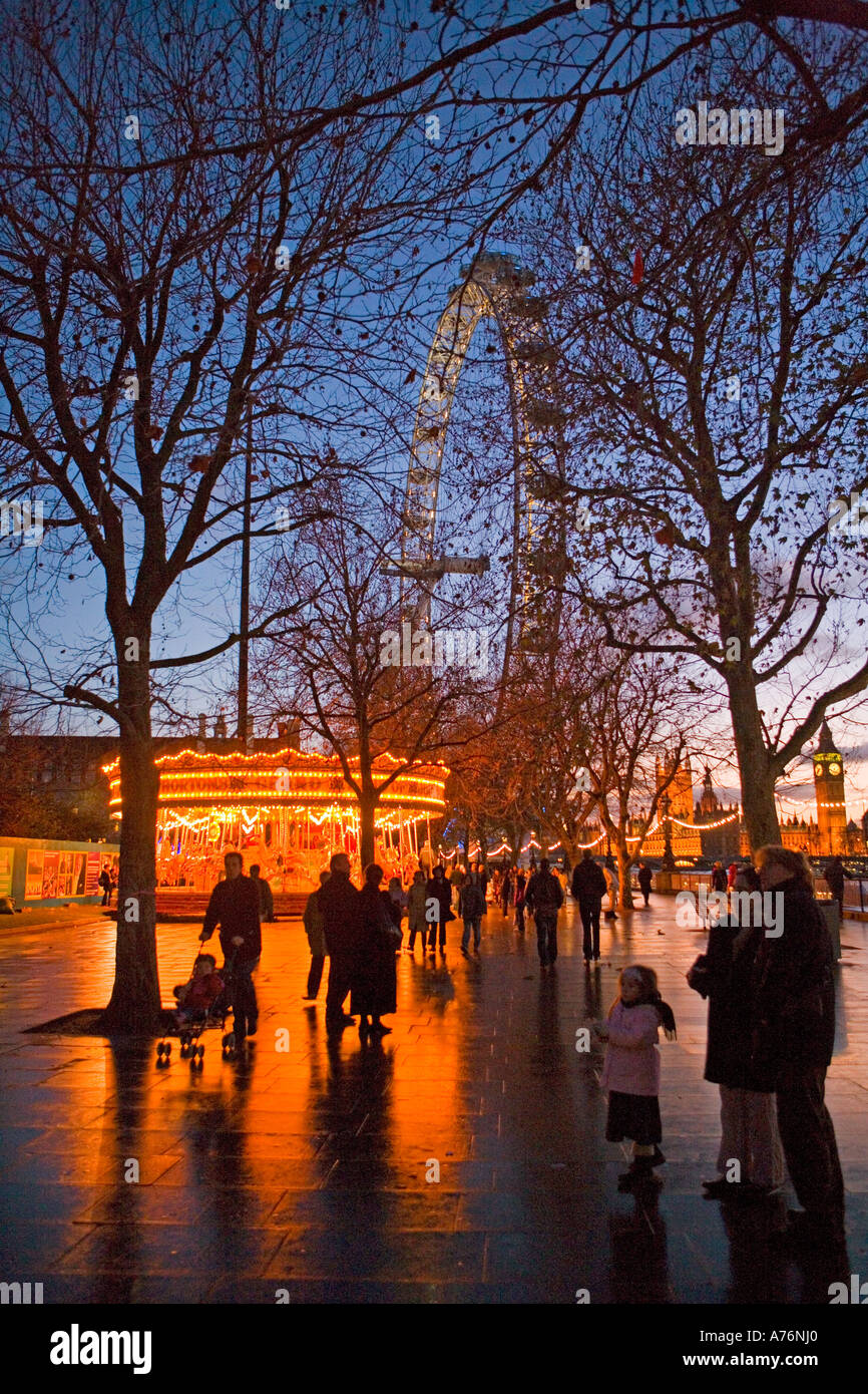 Christmas-period London at dusk   - Warm lights of a Merry-go-round and the British Airways London Eye attractions beckon Stock Photo