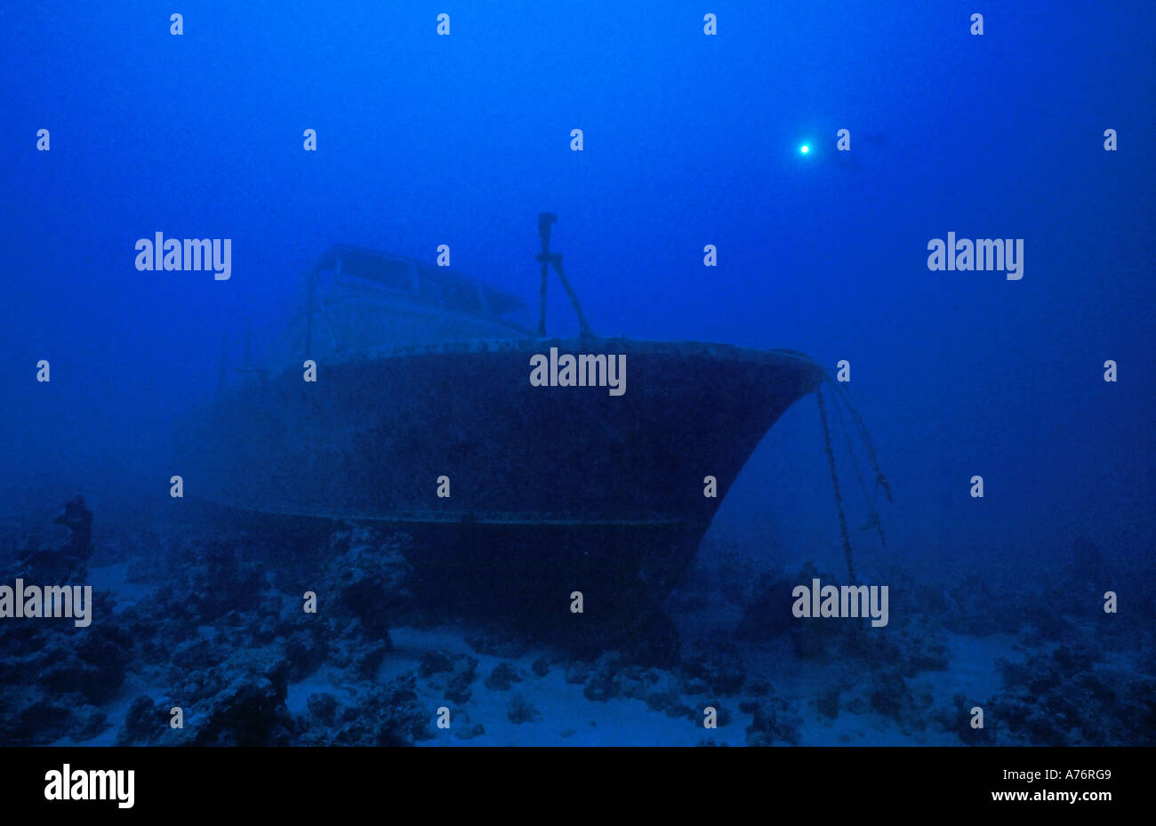 A scuba diver with a torch exploring a sunken ship wreck in murky water. Stock Photo