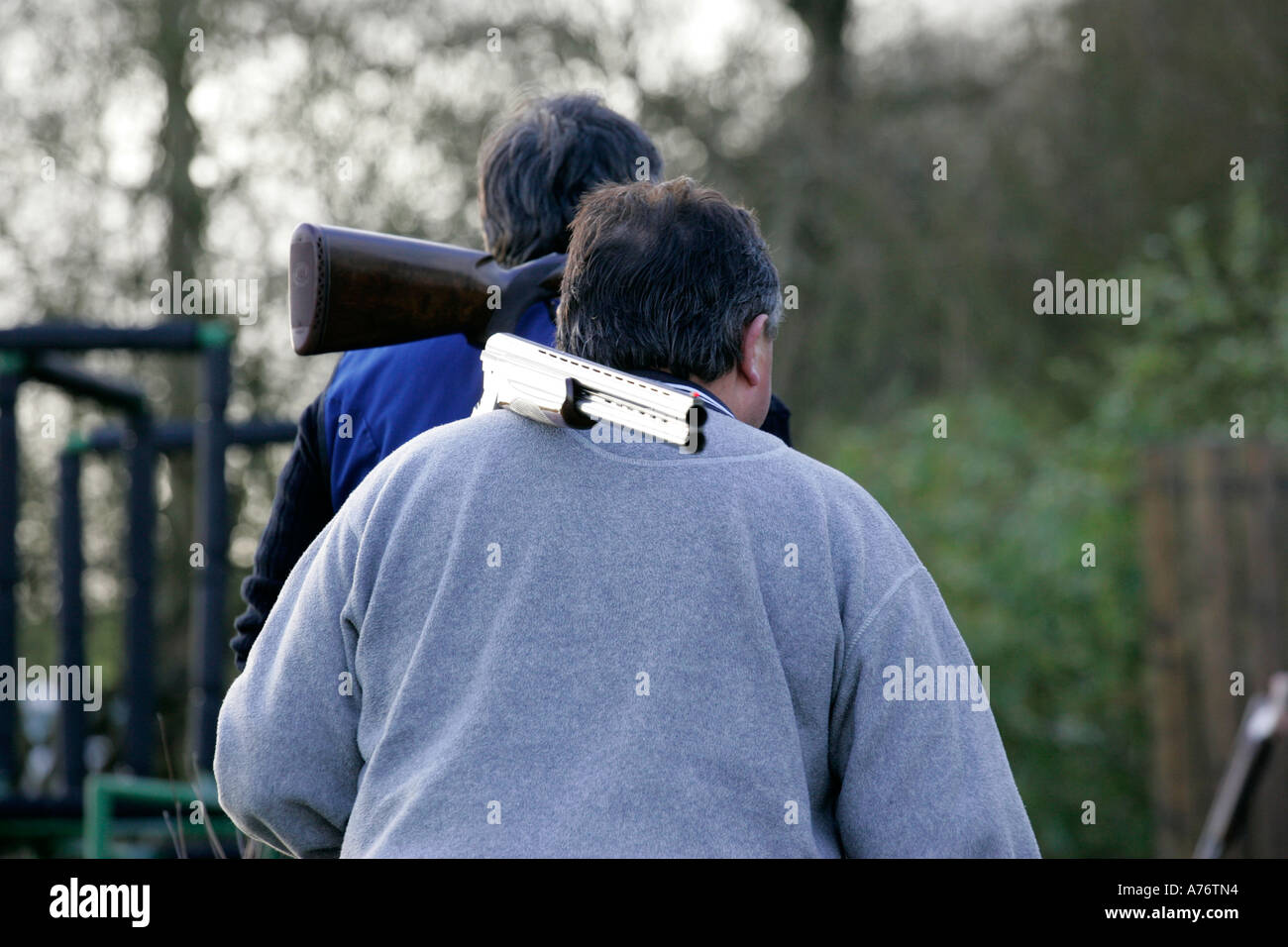 two men carrying shotguns broken on their shoulders back to safe area