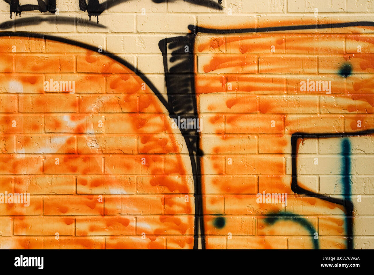 Wall painting brick orange black street art graffiti number in orange on concrete wall Stock