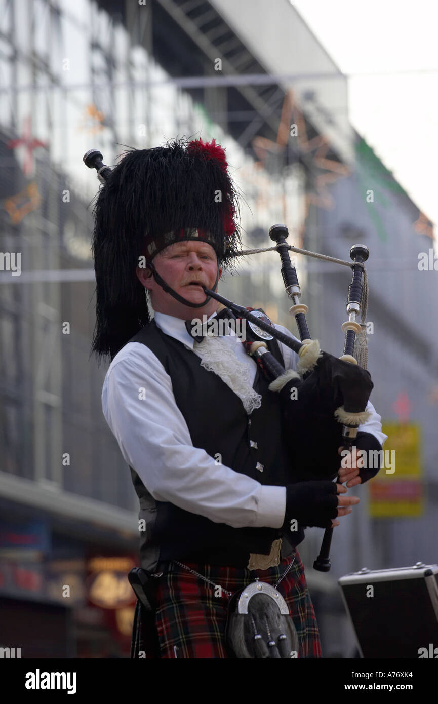bagpipe player in full dress kilt playing bagpipes in pedestrian area