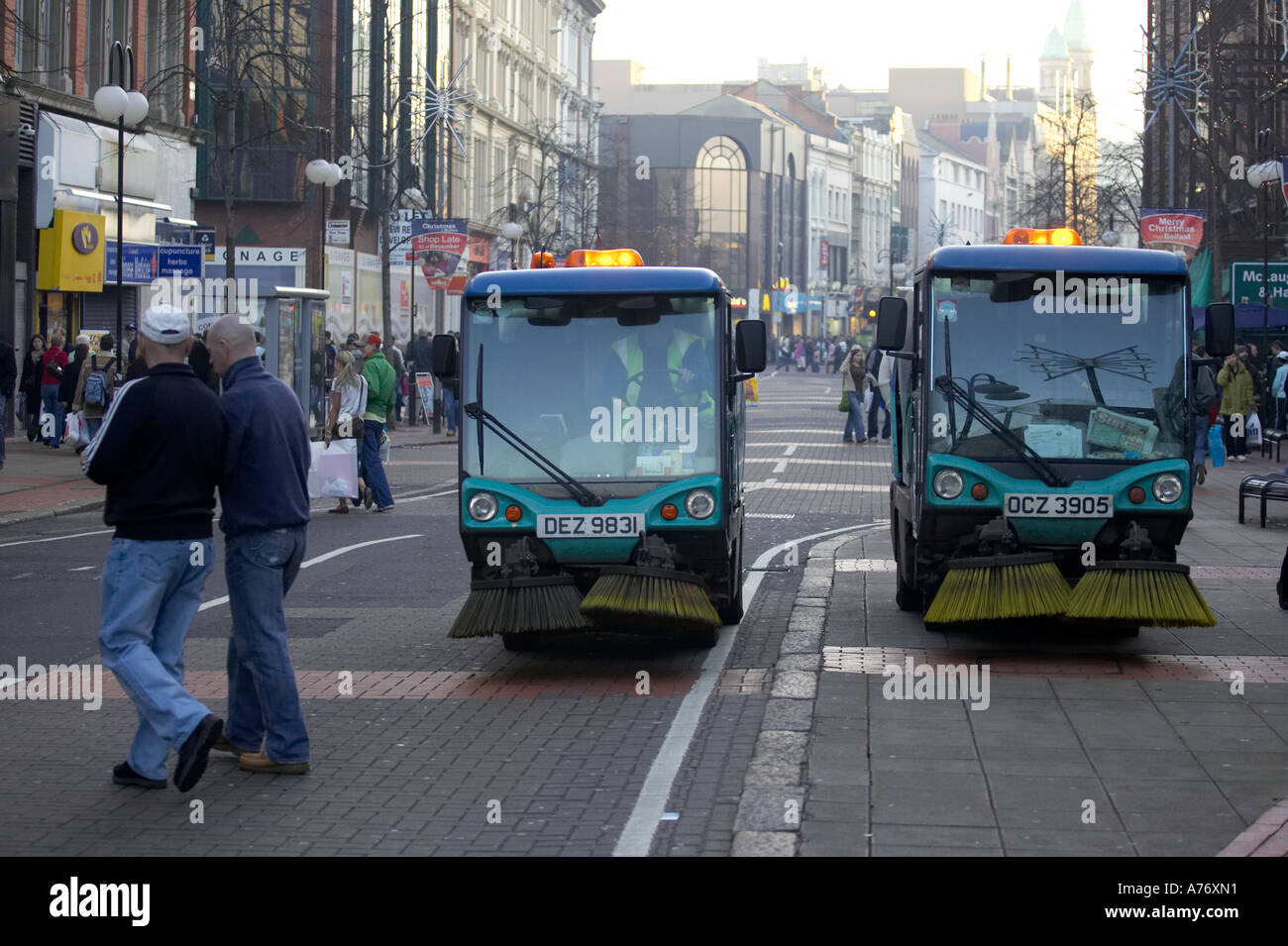 pedestrians walk past two street sweeping machines in Royal Avenue