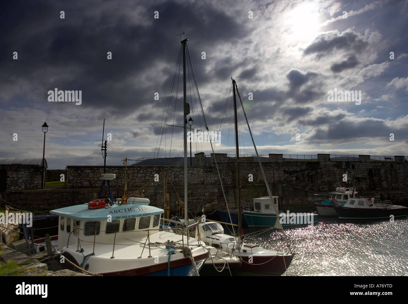 fishing boats tied up in the harbour under stormy skies Carnlough Village county Antrim Northern Ireland Stock Photo