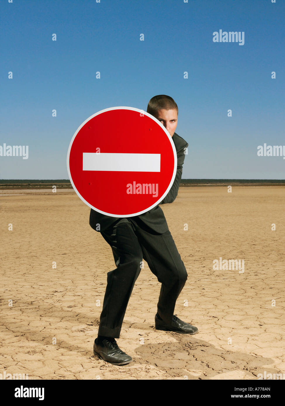 Businessman holding 'no entry' sign in desert, full length Stock Photo