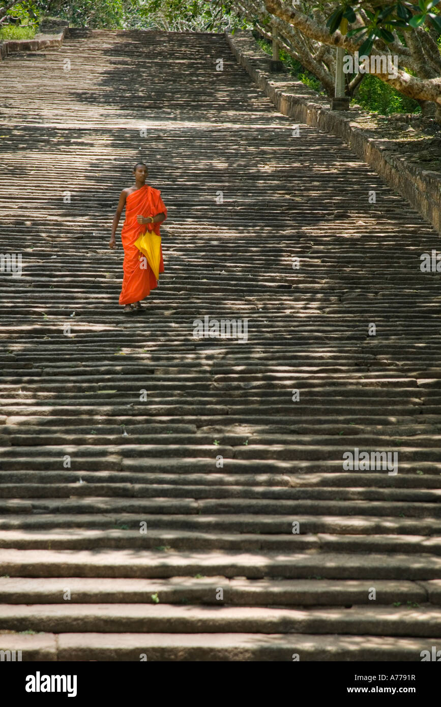 A lone monk descending The Stairway in Mihintale, 1840 granite steps that climb to the dagobas at the top of the hill. Stock Photo