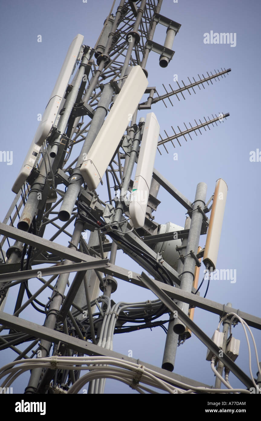 a cluster of mobile cell phone telephone microwave telecommunications aerials and transmitters on a mast in the UK Stock Photo