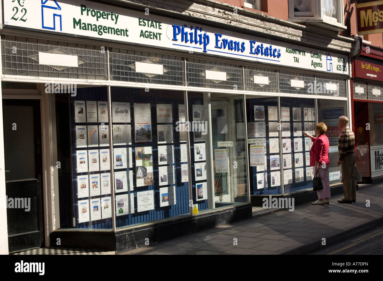 Middle aged couple looking at property details in the window of Philip  Evans estate agent, Aberystwyth Wales Stock Photo - Alamy