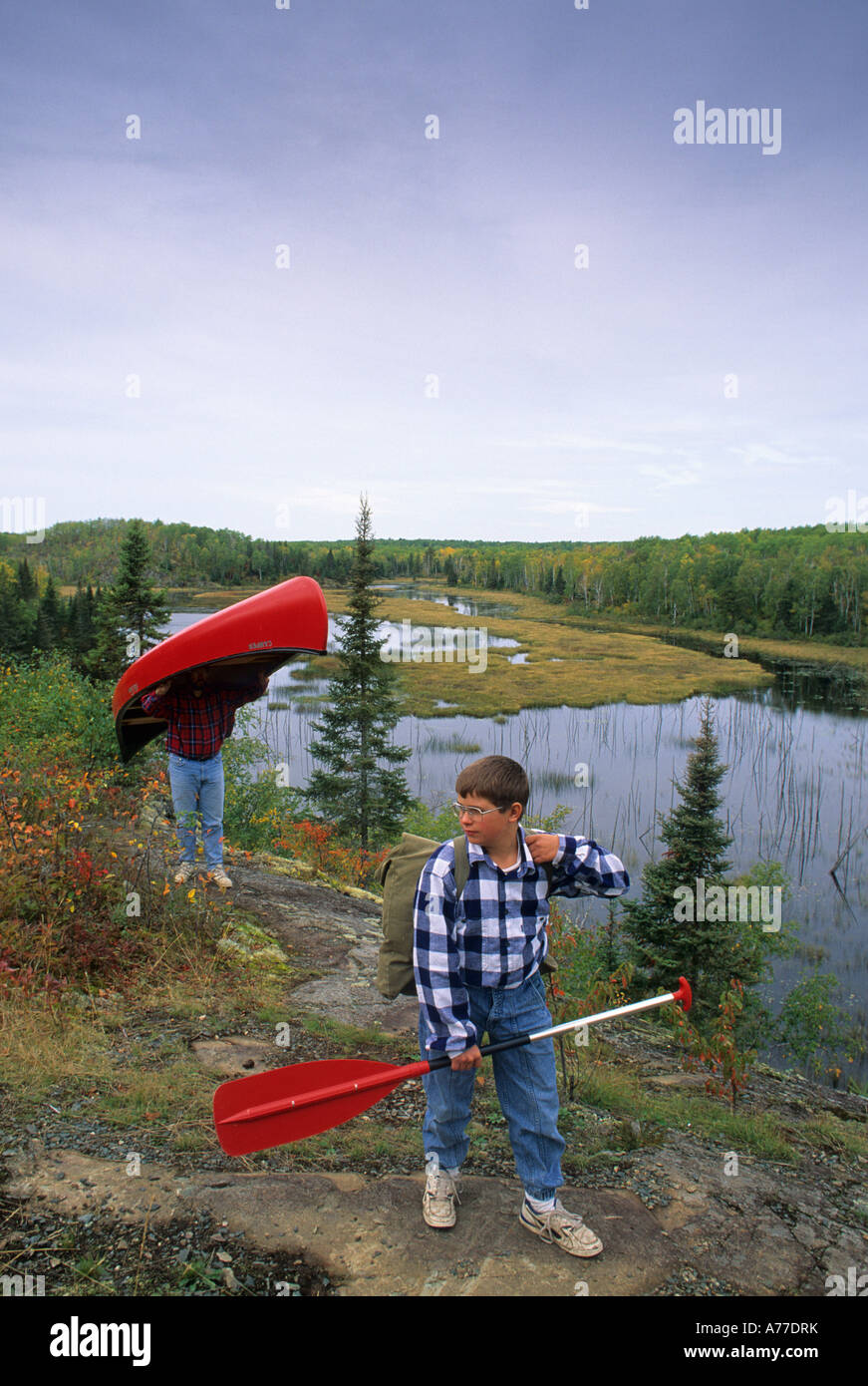 DAD AND SON PORTAGE CANOE NEAR WOOD LAKE IN THE BOUNDARY WATERS CANOE AREA WILDERNESS, NORTHERN MINNESOTA. LATE SUMMER. Stock Photo