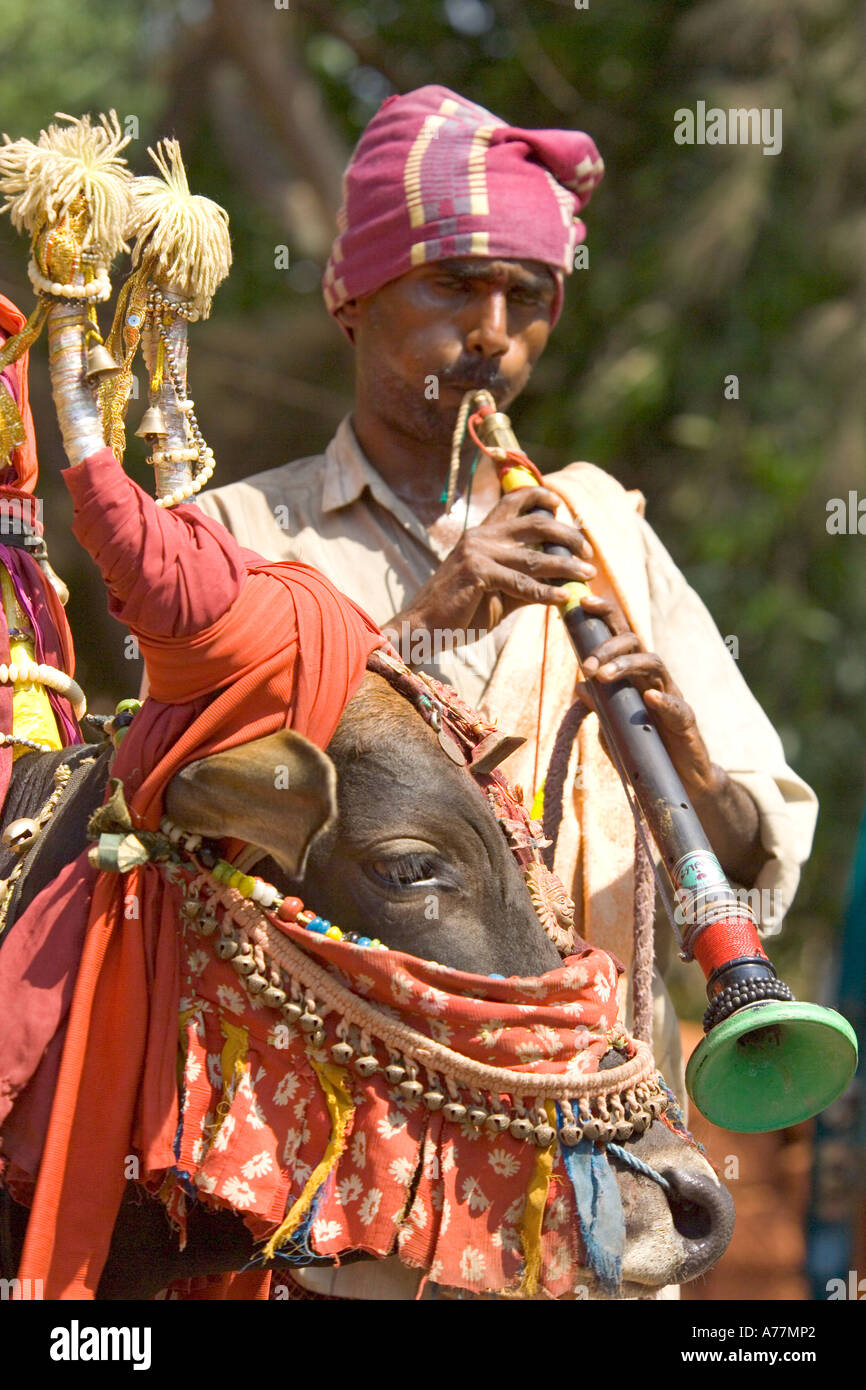 A Indian man playing a nadaswaram oboe type with his colourful