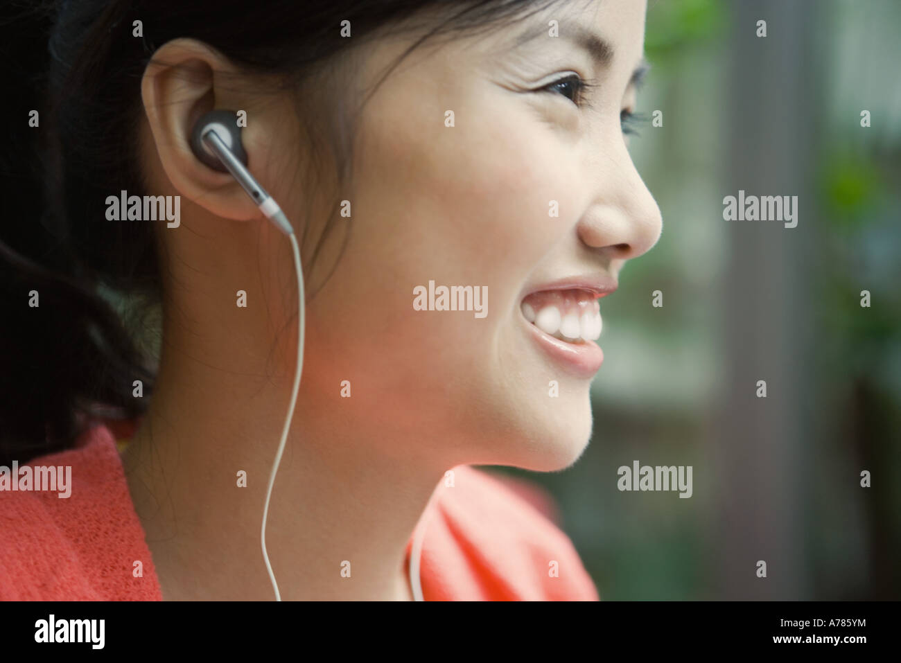 Young woman wearing earphones, smiling, close-up, profile Stock Photo