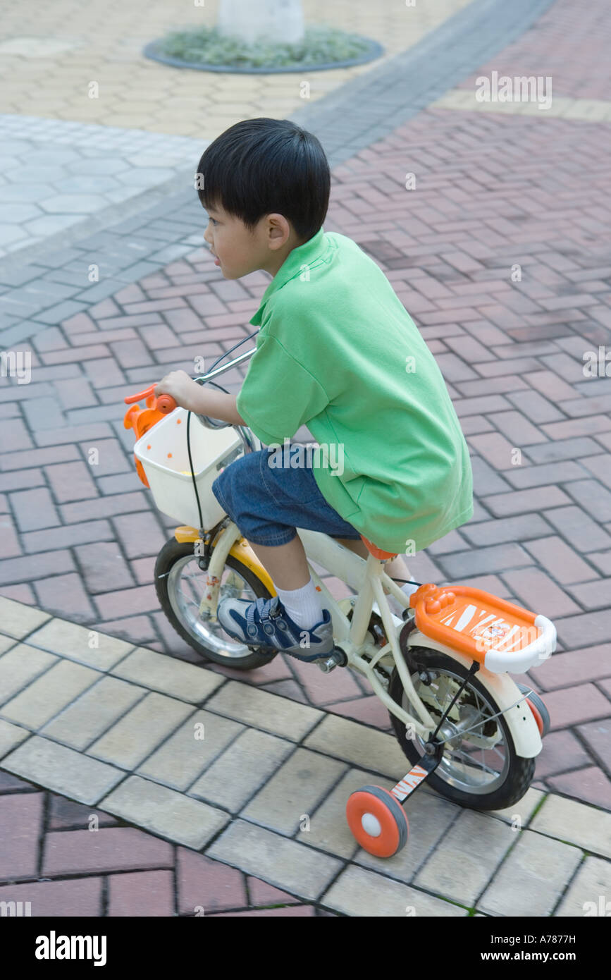 Boy riding bike with training wheels Stock Photo Alamy