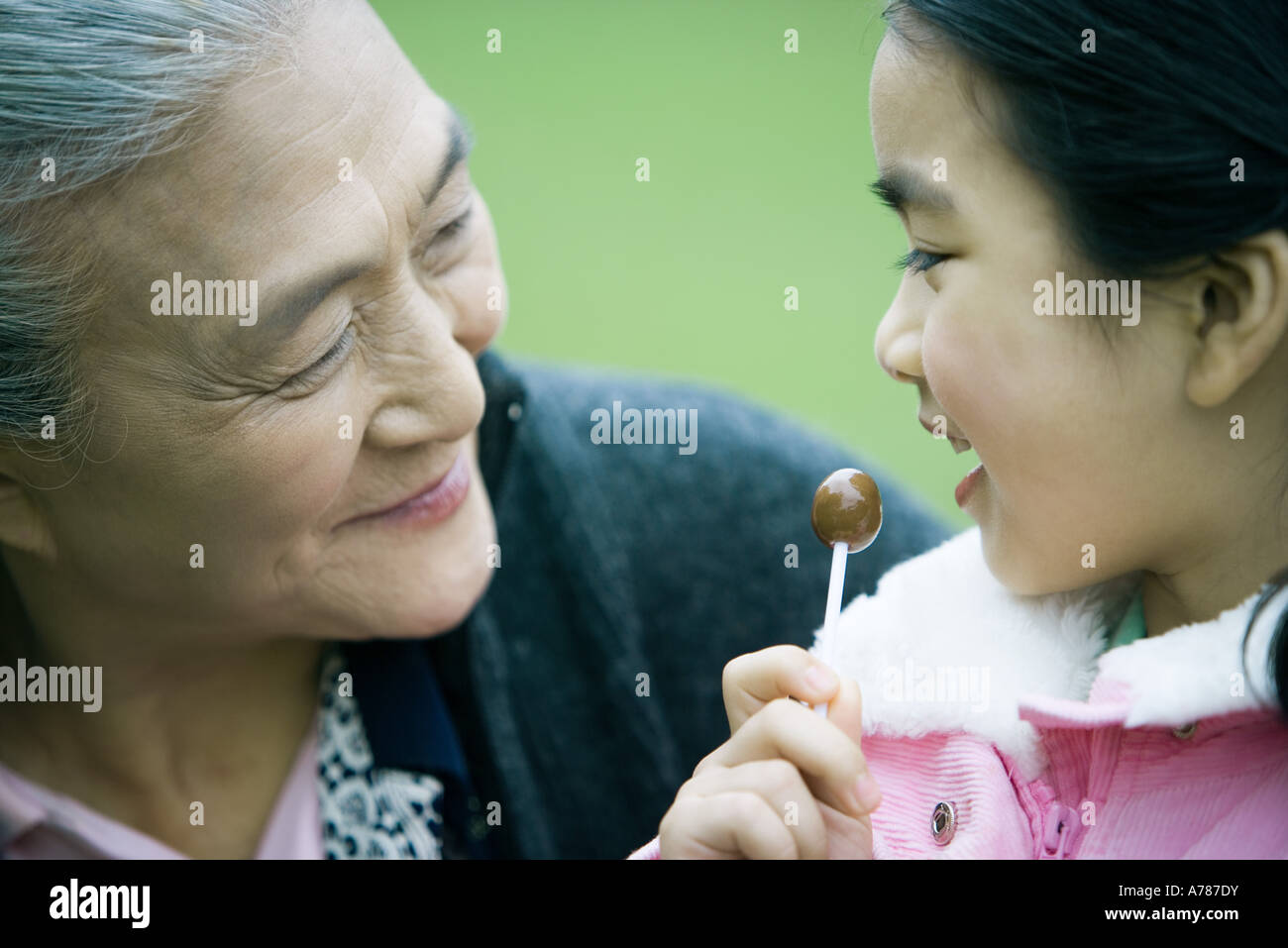 Girl eating lollipop, looking at grandmother, close-up Stock Photo