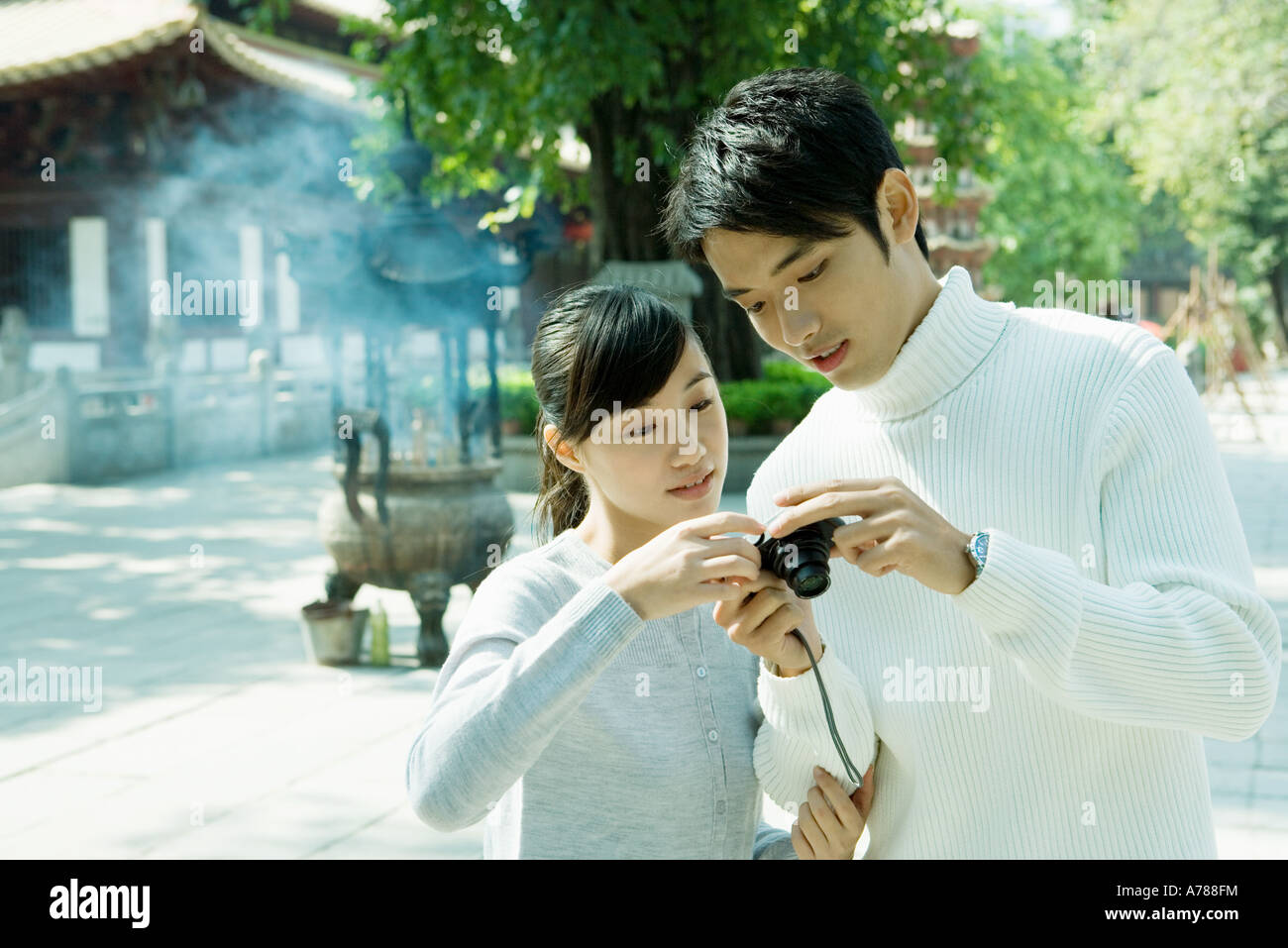 Couple looking at digital camera, temple in background Stock Photo