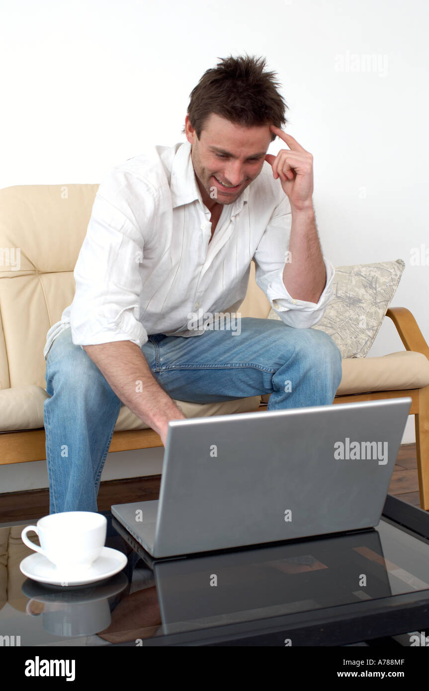 man on sofa working on a laptop computer home office working from home Stock Photo