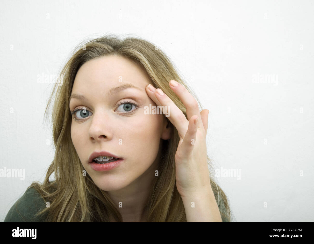 Teenage girl with finger on temple, leaning toward camera, portrait Stock Photo