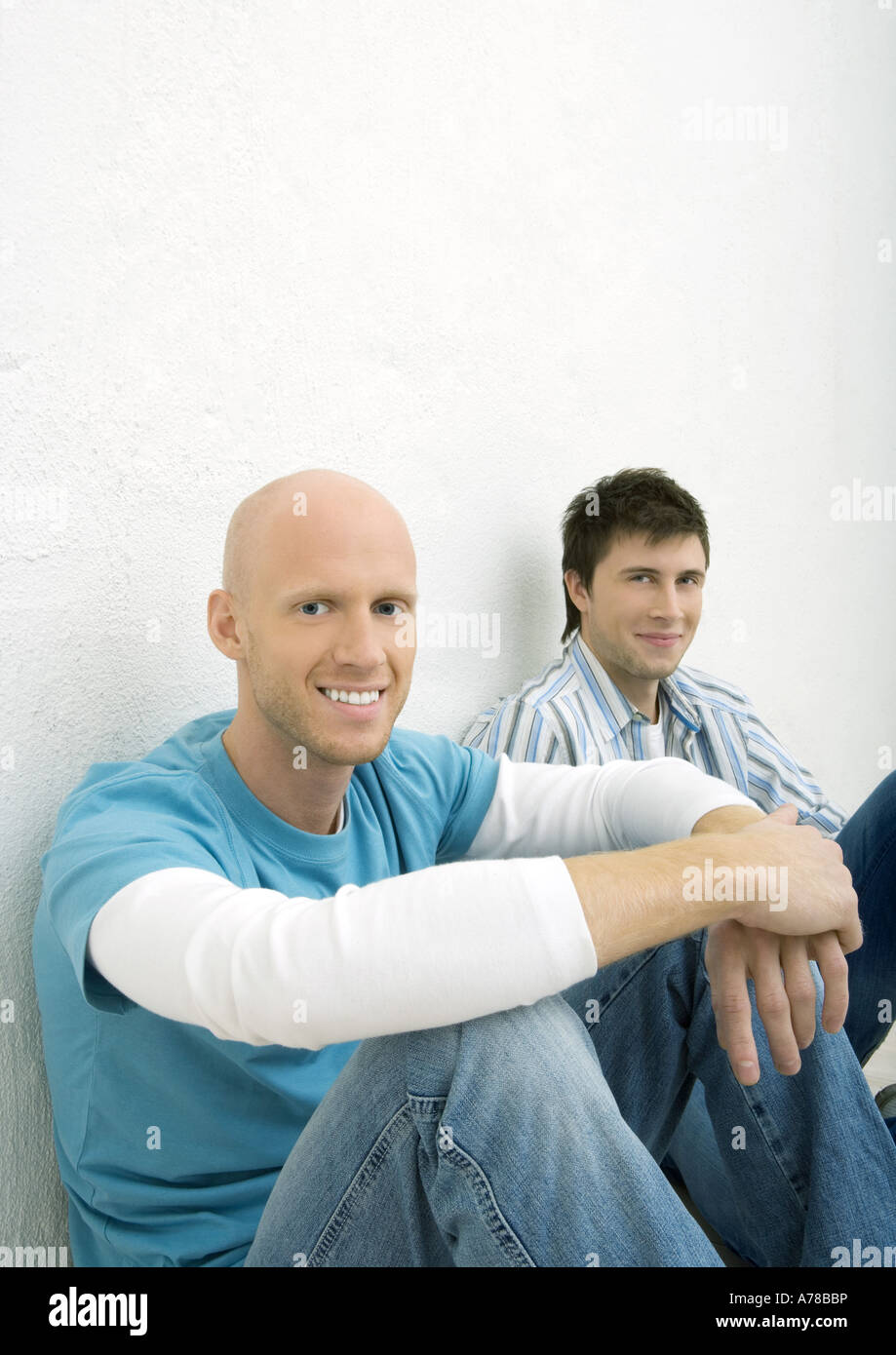 Two young men sitting on floor, looking at camera Stock Photo - Alamy