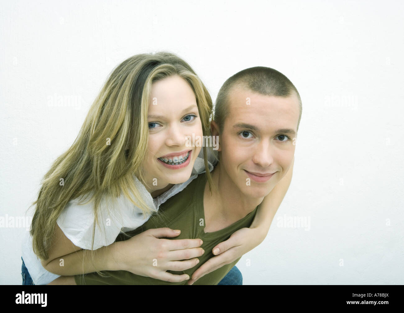 Young couple, teenage girl on young man's back, white background Stock Photo