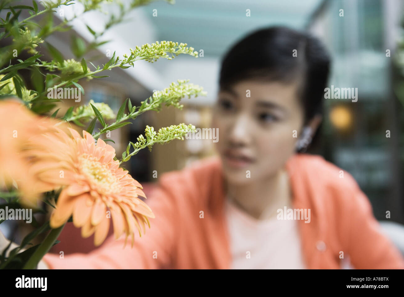 Young woman and flower arrangement, focus on flower in foreground Stock Photo
