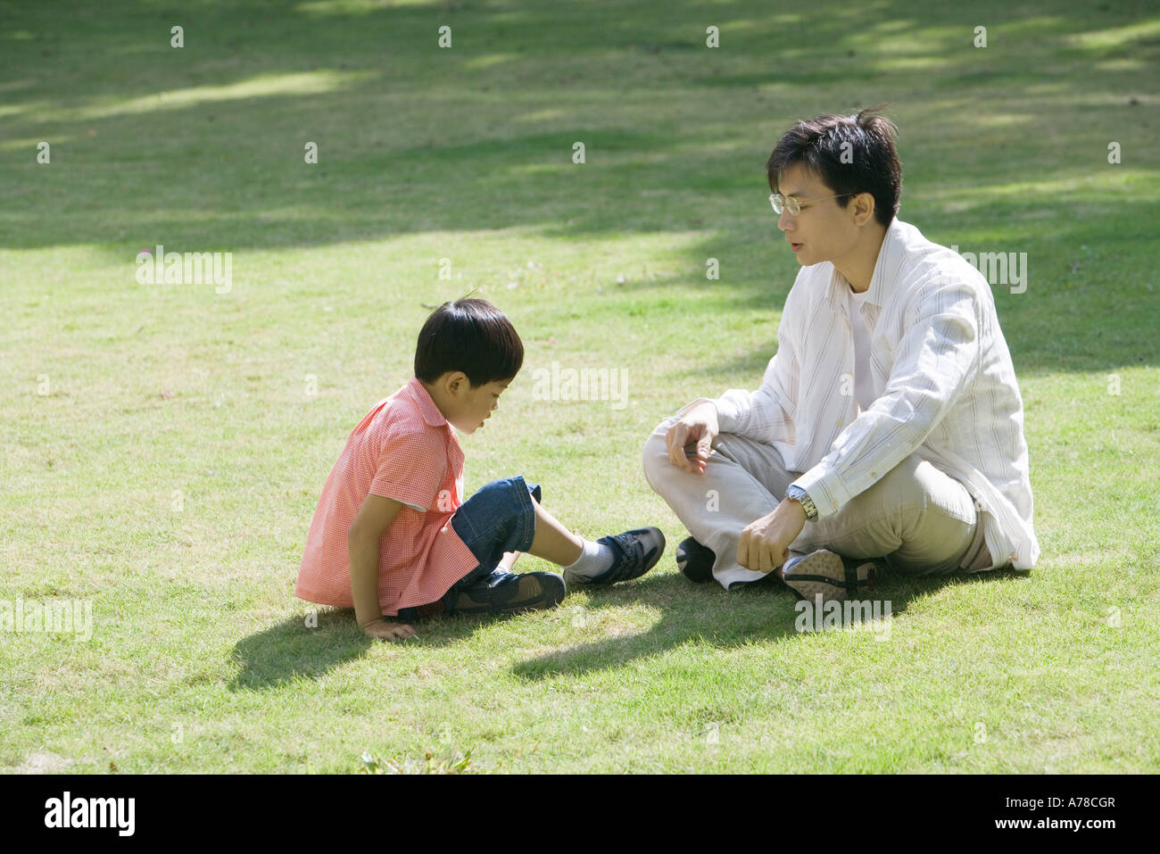 Father and son sitting on grass Stock Photo - Alamy