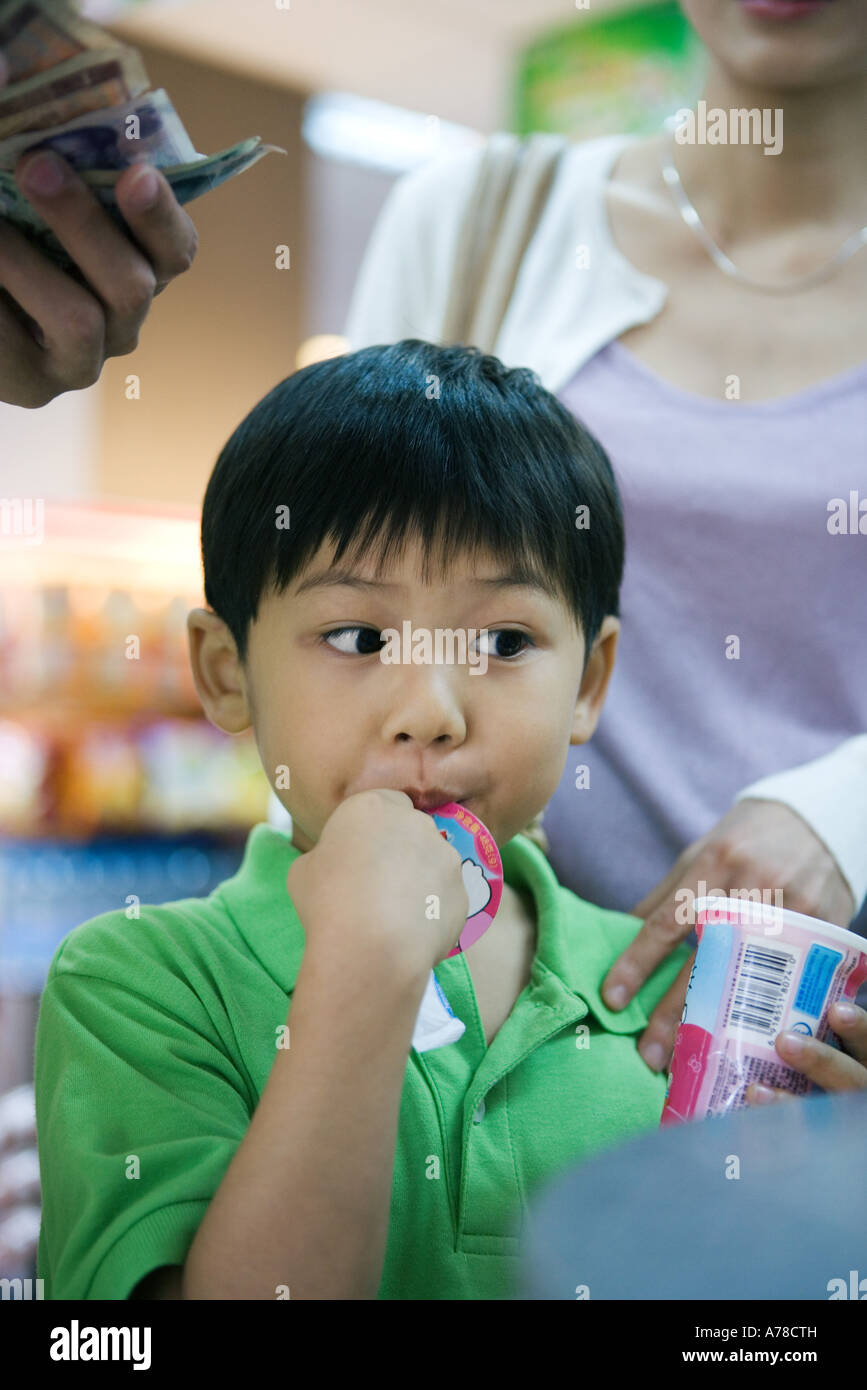 Boy eating sweet snack at checkout counter Stock Photo