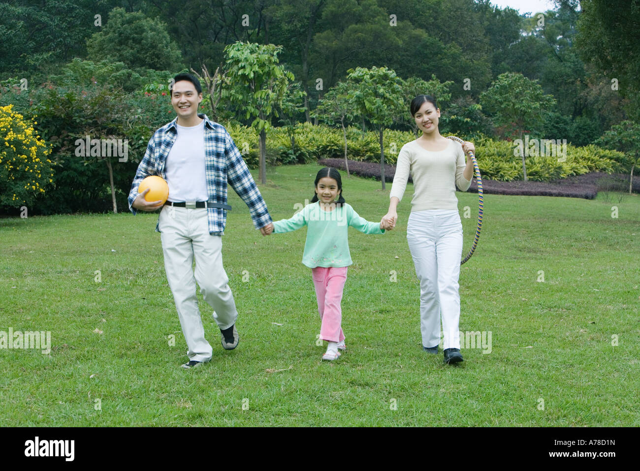 Girl walking hand in hand with parents, full length Stock Photo - Alamy