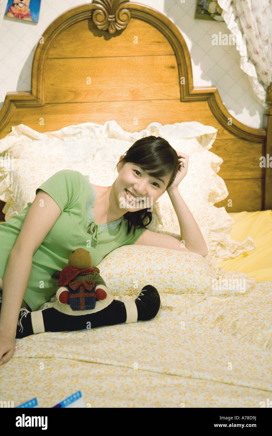 Young woman reclining on bed, smiling at camera Stock Photo - Alamy