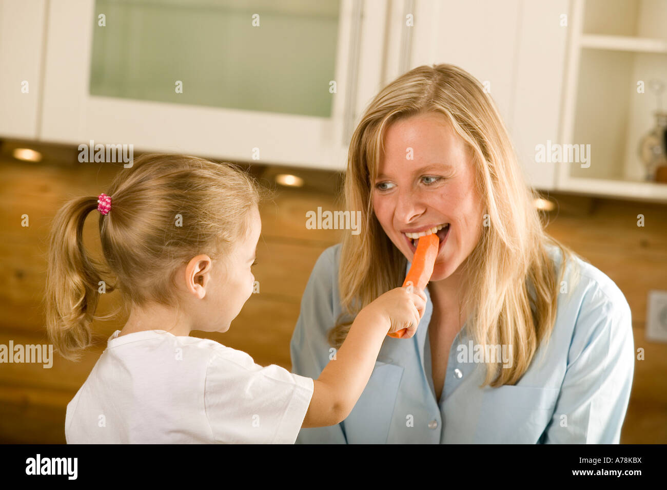 little girl feeding her mother a carrot organic vegetables Stock Photo ...
