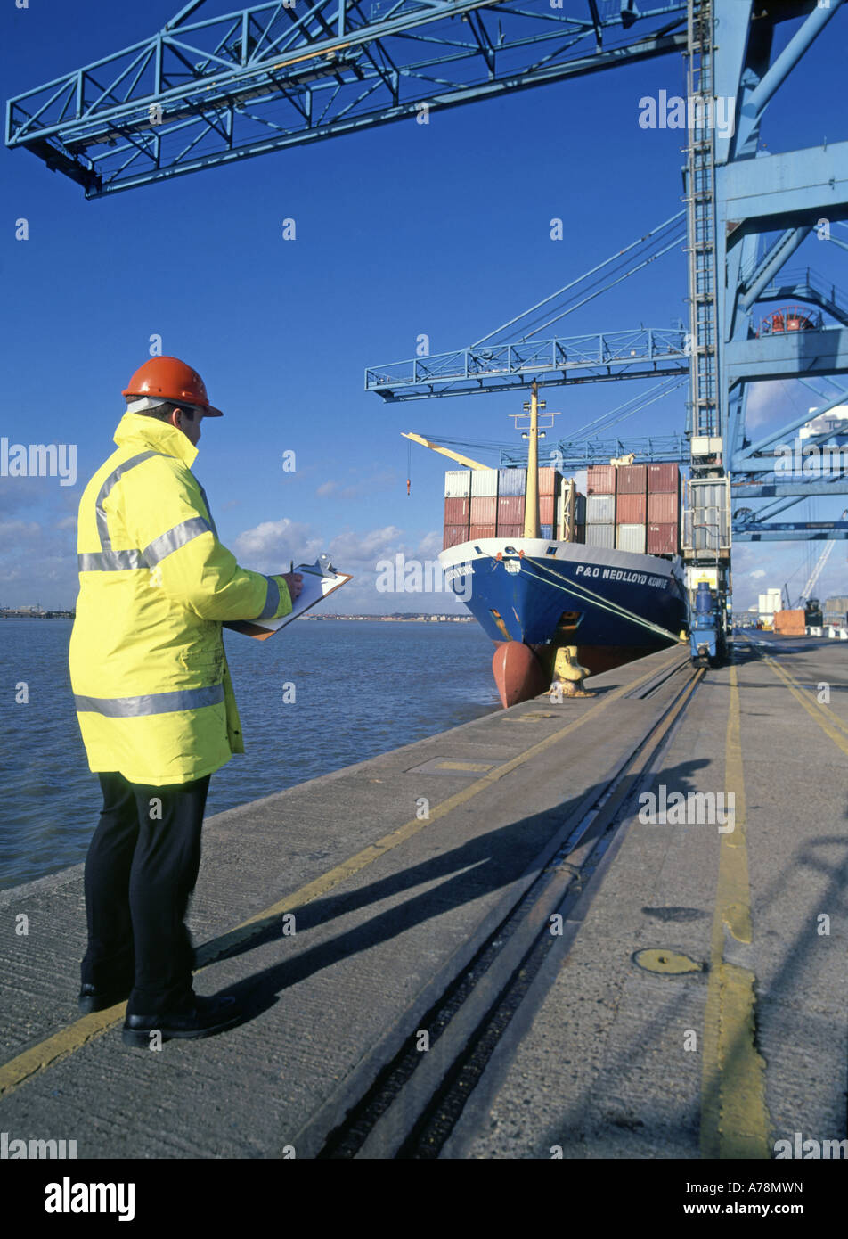 Supervisor checking procedures at Tilbury dock during handling of containers to and from moored boxship freighter Stock Photo