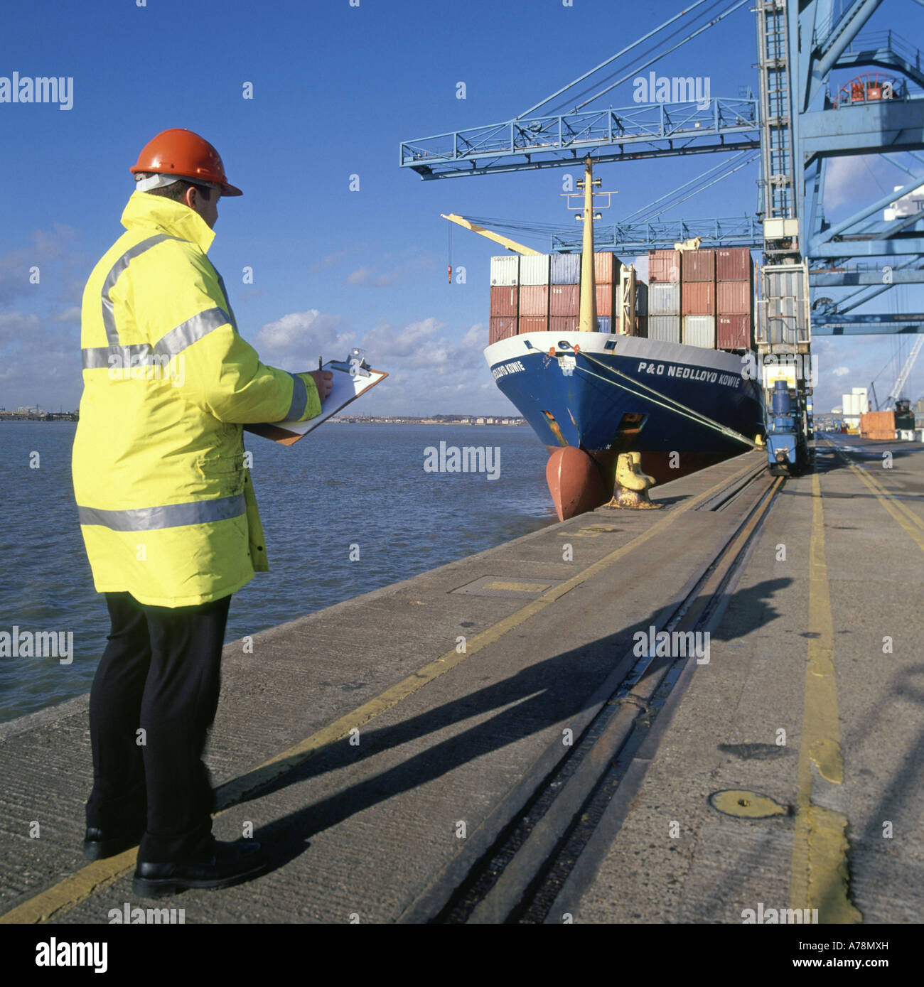 Supervisor checking procedures at Tilbury dock during handling of containers to and from moored freighter Stock Photo