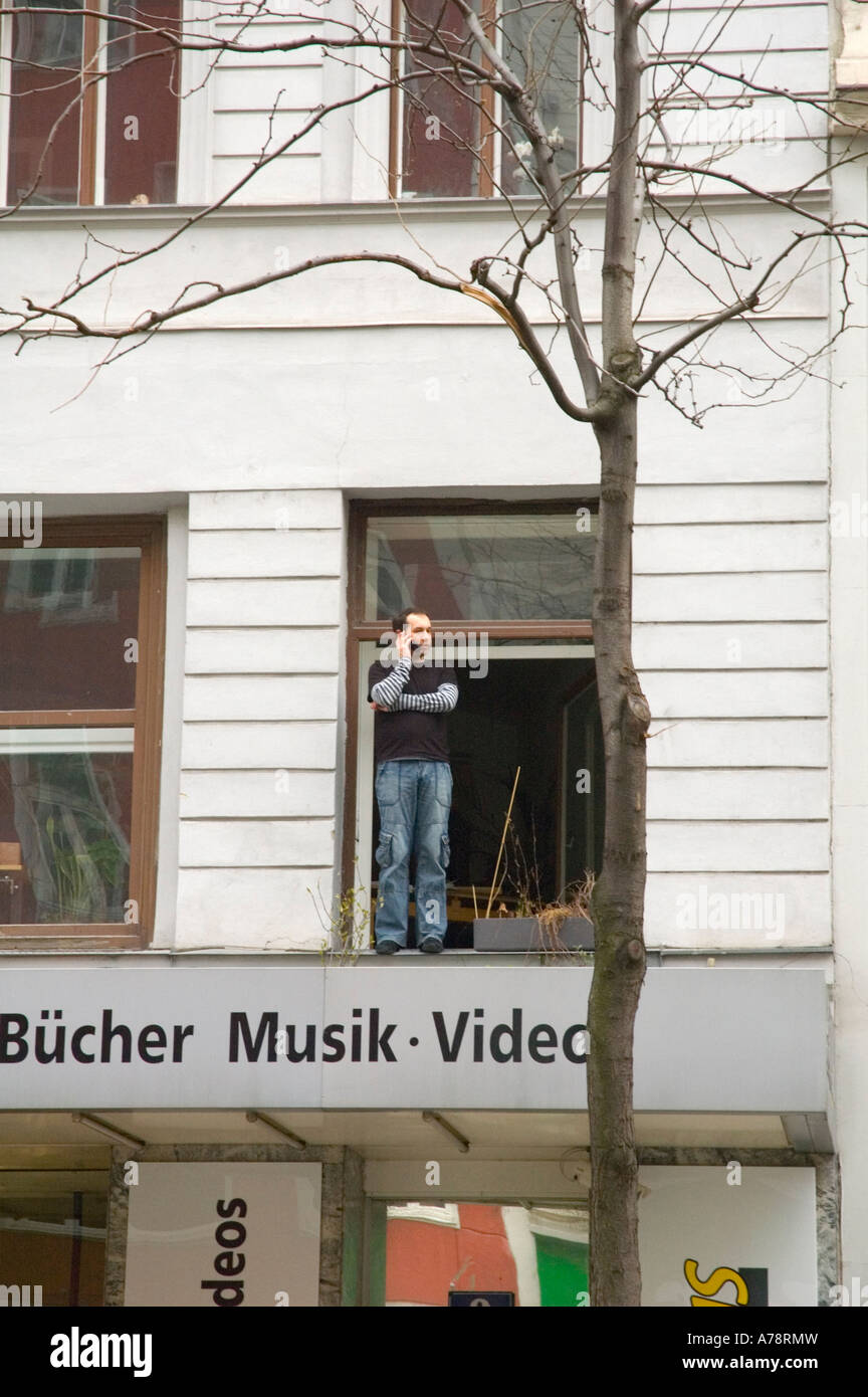 A man talking on mobile on a windowsill along Mariahilferstrasse central Vienna Austria EU Stock Photo
