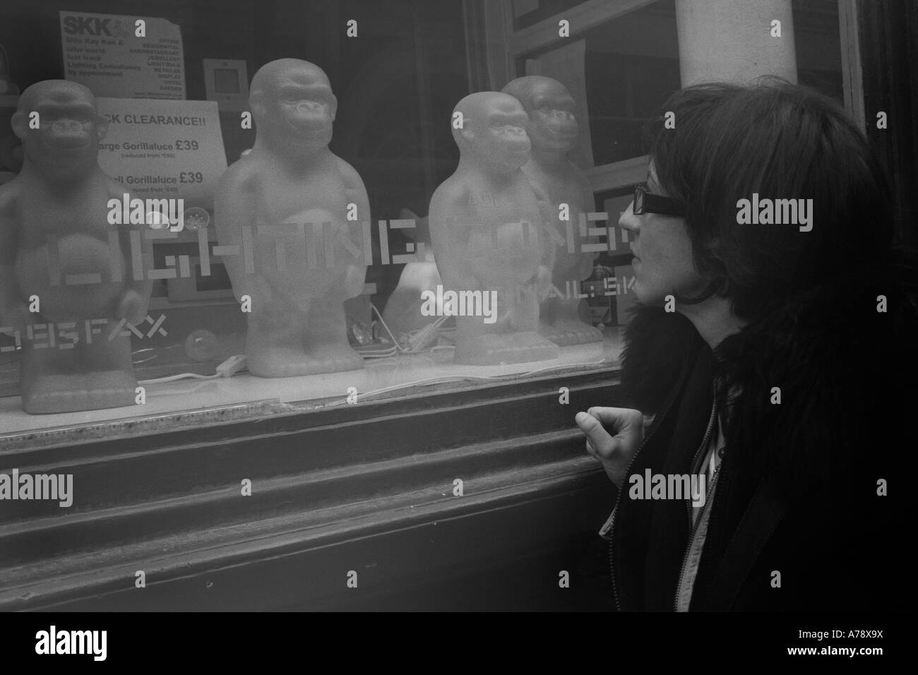 GORILLAS IN THE MIST.  Young woman window-shopper gazes at gorilla  lighting models in Soho, London. Stock Photo