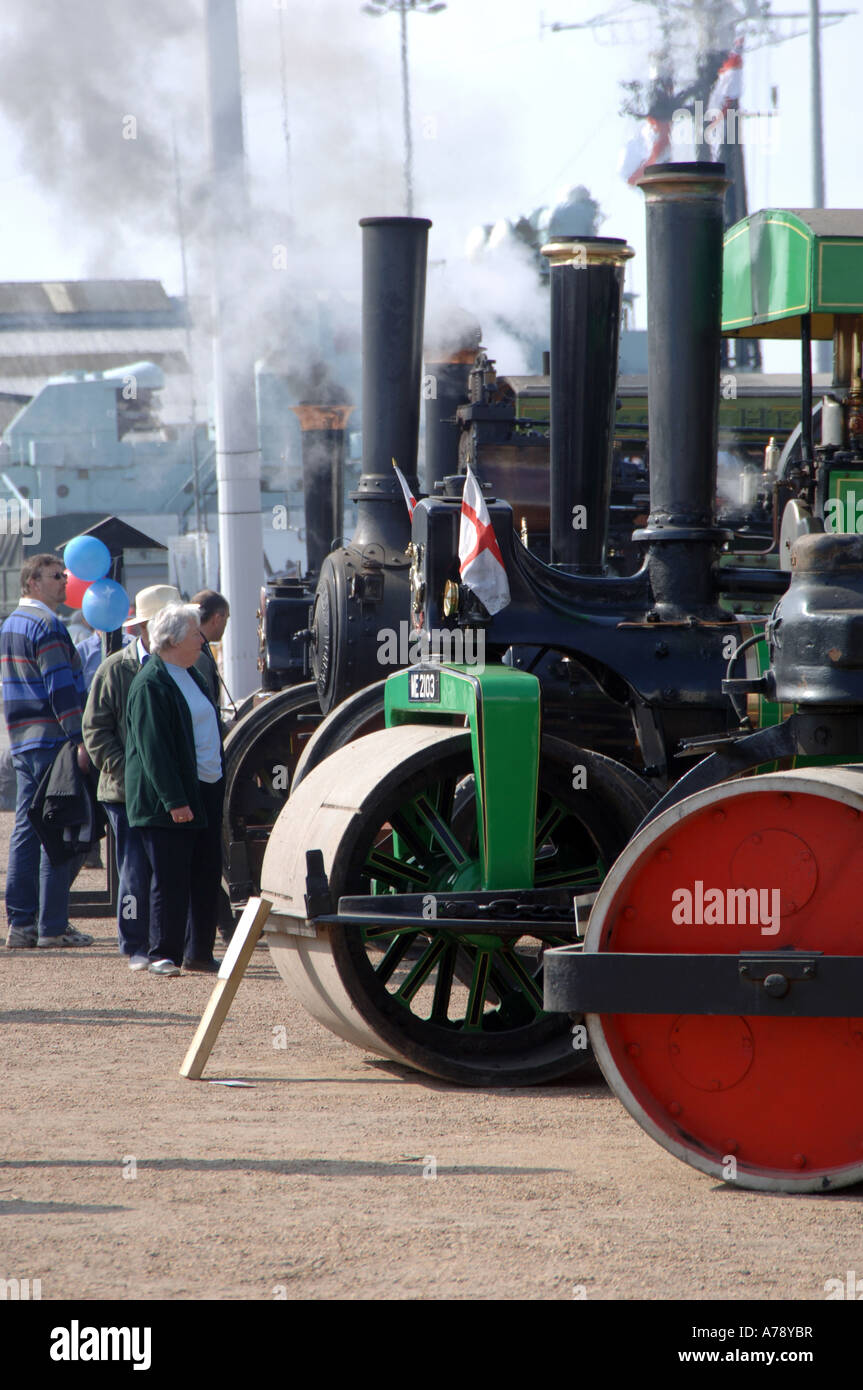 steam rollers and traction engines line up in a mass of smoke and steam, dwarfing the viewing people around them Stock Photo
