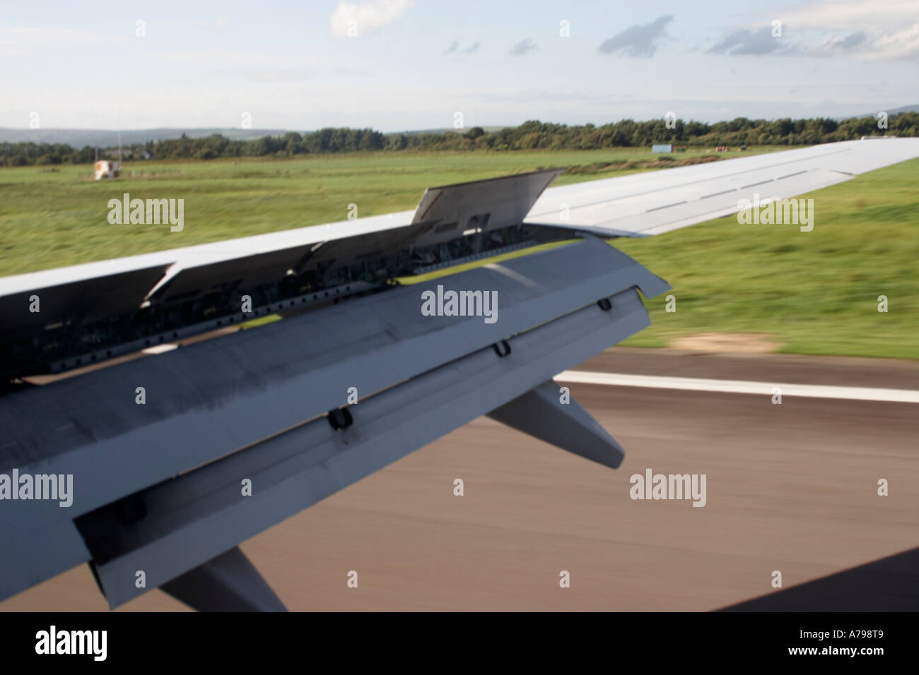 Boeing 737 aircraft wing with flaps down and lowered and airbrakes or spoilers up Landing on a runway Stock Photo