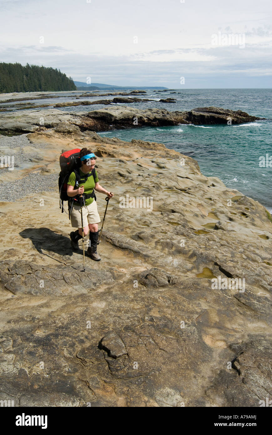 A woman hikes along the sandstone shelf near Hole in the wall on BC s West Coast Trail Stock Photo