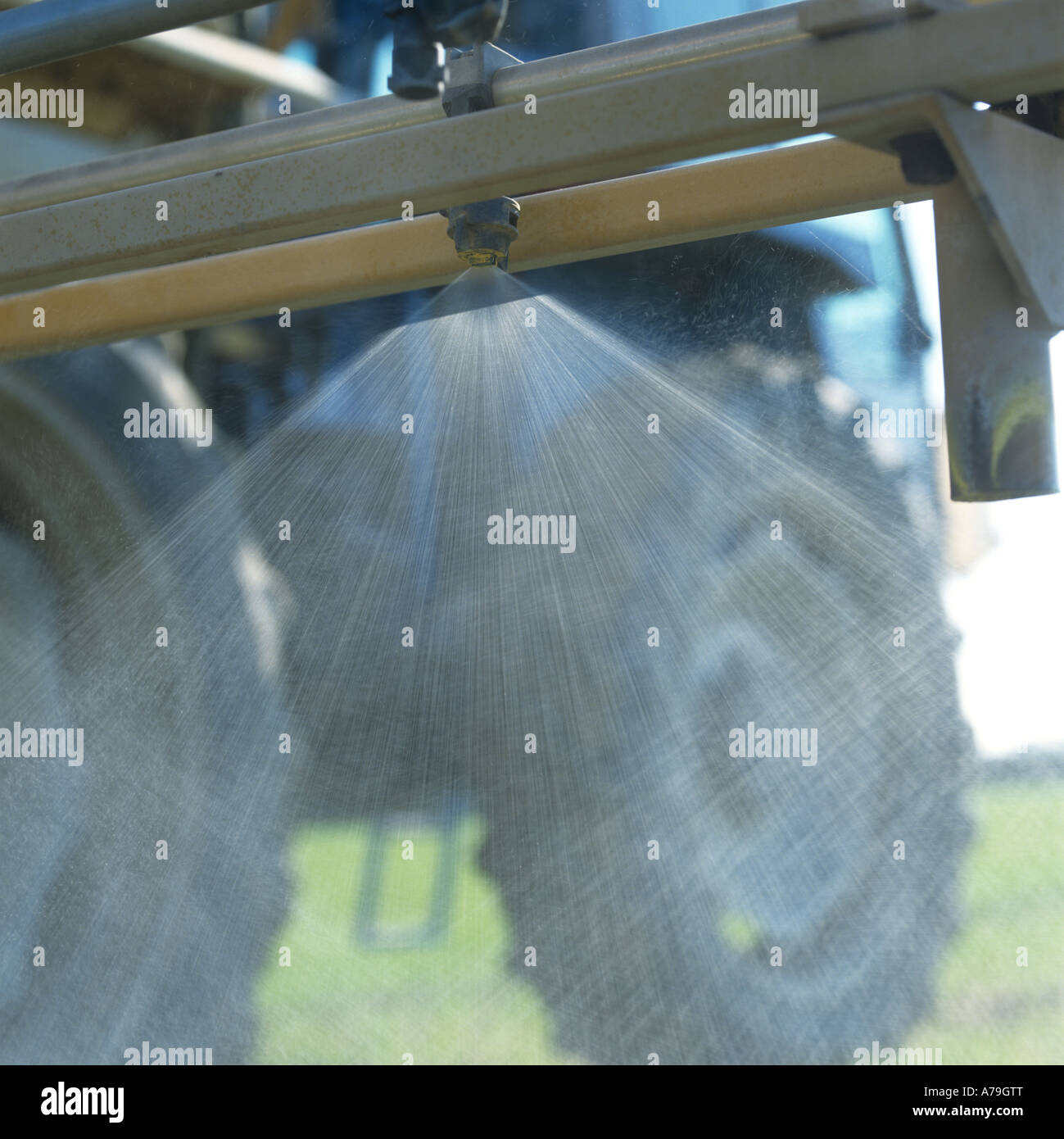 Spray fan pattern from the jet nozzle on a tractor sprayer boom Stock Photo